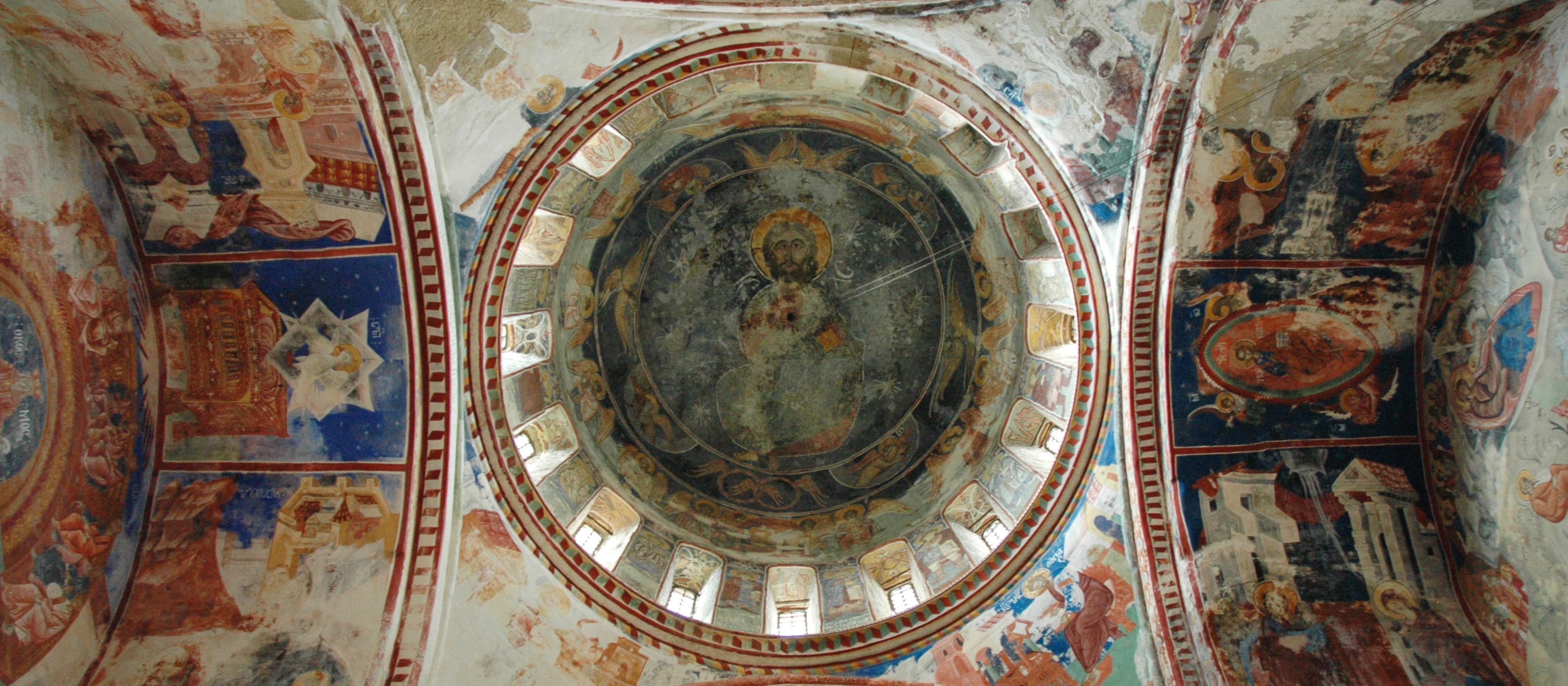 Ancient Georgian Orthodox church interior with ornate Byzantine frescoes, golden dome, and traditional religious iconography